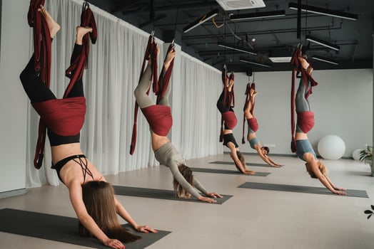 A group of women are hanging upside down on hanging hammocks. Fly yoga in the gym photo