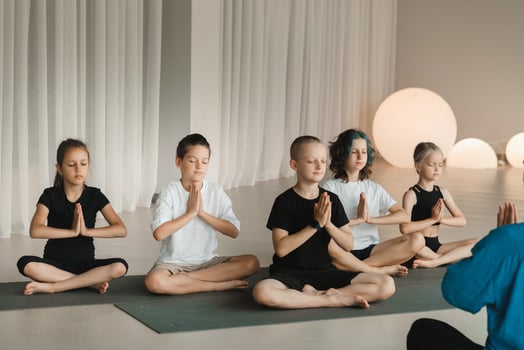 Children sit on mats in the lotus position in Yoga classes. Children's yoga photo