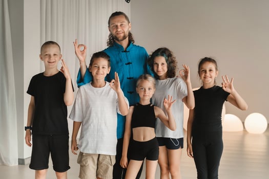 A joint portrait of a yoga coach and children standing in a fitness room photo