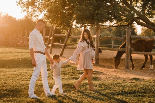 A stylish family in the countryside at sunset. A pregnant woman with her husband and son in nature photo