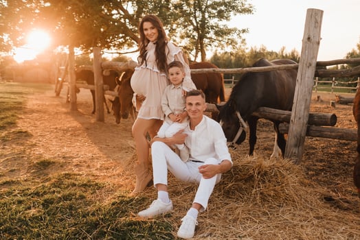 Happy family near horses at a farmer's ranch at sunset photo