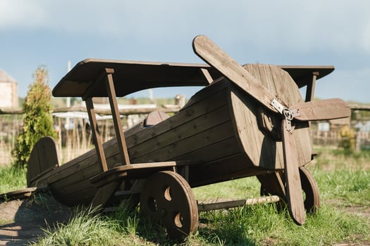 A wooden model of an airplane standing on the street in summer photo