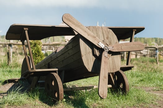 A wooden model of an airplane standing on the street in summer photo