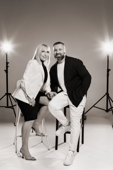 A man and a woman in strict clothes pose against the background in the studio photo