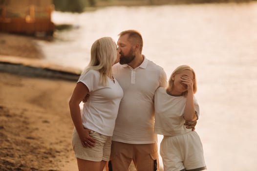 Happy family - father, mother and daughter in light clothes having fun together on the beach in summer photo