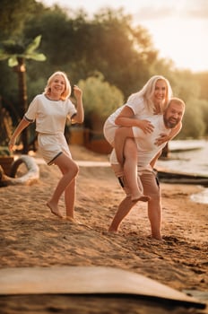 Happy family - father, mother and daughter in light clothes having fun together on the beach in summer photo
