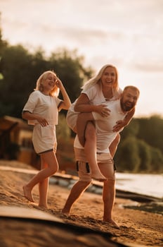 Happy family - father, mother and daughter in light clothes having fun together on the beach in summer photo