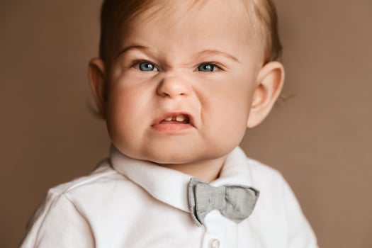 Portrait of a little boy in a white shirt with a bow tie grimacing on camera photo