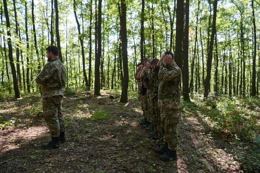 A dedicated group of soldiers engages in Islamic prayer amidst the challenging and perilous conditions of a military operation in dense forested areas photo