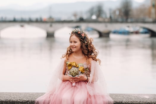 a little girl in a pink Princess dress with a bouquet in her hands walks through the old city of Zurich.Portrait of a girl in a pink dress on a city street in Switzerland photo