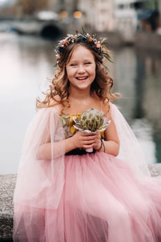 a little girl in a pink Princess dress with a bouquet in her hands walks through the old city of Zurich.Portrait of a girl in a pink dress on a city street in Switzerland photo