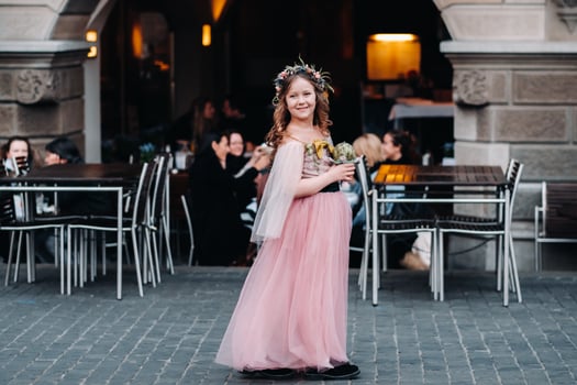 a little girl in a pink Princess dress with a bouquet in her hands walks through the old city of Zurich.Portrait of a girl in a pink dress on a city street in Switzerland photo