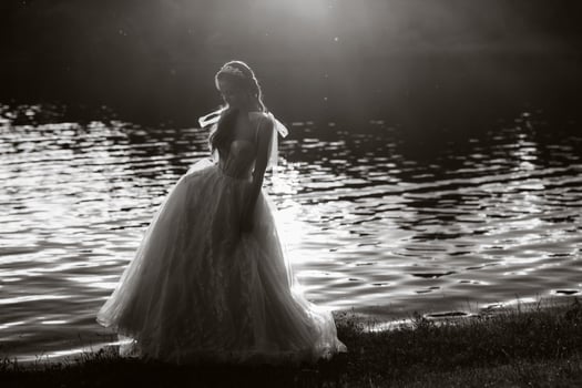 An elegant bride in a white dress enjoys nature at sunset.Model in a wedding dress in nature in the Park.Belarus. black and white photo