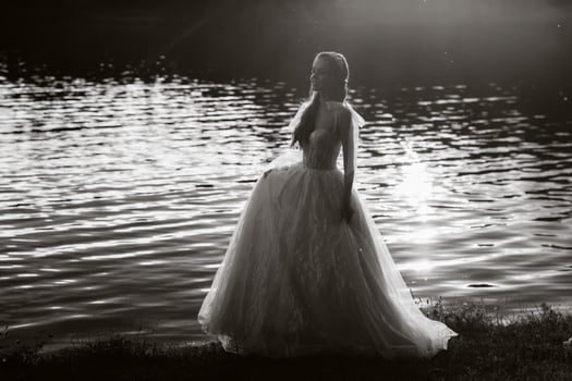 An elegant bride in a white dress enjoys nature at sunset.Model in a wedding dress in nature in the Park.Belarus. black and white photo