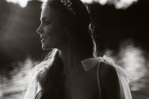 An elegant bride in a white dress enjoys nature at sunset.Model in a wedding dress in nature in the Park.Belarus. black and white photo
