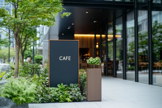 Cafe sign surrounded by greenery in front of a classic building with ornate decor photo