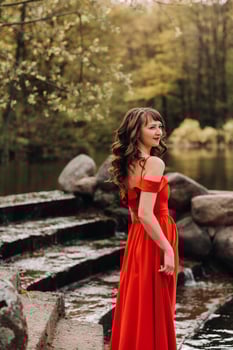 girl in a long red dress near the lake in the Park at sunset. photo