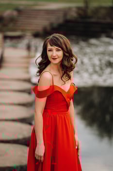 girl in a long red dress near the lake in the Park at sunset. photo