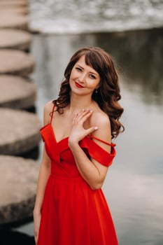 girl in a long red dress near the lake in the Park at sunset. photo