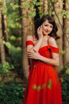 Spring Portrait of a laughing girl in a long red dress with long hair walking in the Park in the woods photo