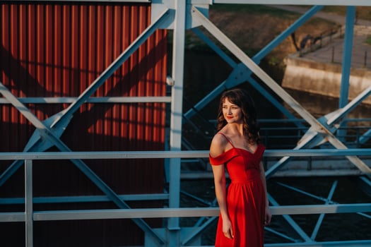 A girl in a red dress on a dam near a river at sunset photo