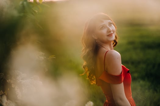 a beautiful girl in spring in a red dress is walking in a field at sunset. Taken from the air by a quadrocopter photo