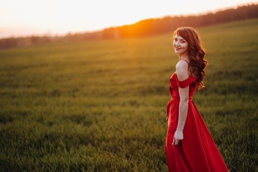 a beautiful girl in spring in a red dress is walking in a field at sunset. Taken from the air by a quadrocopter photo