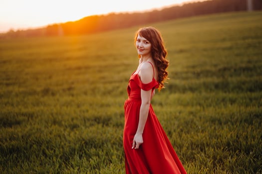 a beautiful girl in spring in a red dress is walking in a field at sunset. Taken from the air by a quadrocopter photo