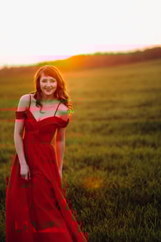 a beautiful girl in spring in a red dress is walking in a field at sunset. Taken from the air by a quadrocopter photo
