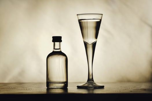 On the table are a bottle of alcohol and a full glass on a beautiful background photo