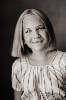 A happy child, a little girl in a gray T-shirt on a beige background. black and white photo
