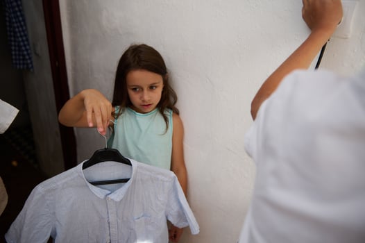Young girl holding a shirt on a hanger indoors photo