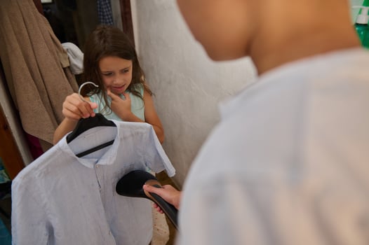 Young girl learning to iron clothes in laundry room photo