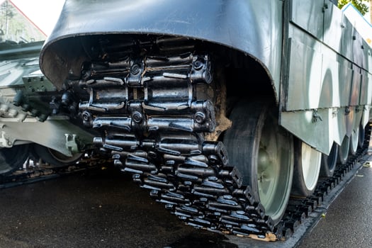Tracked armor close-up. Black tracks and large rubberized rollers. Tank chassis photo