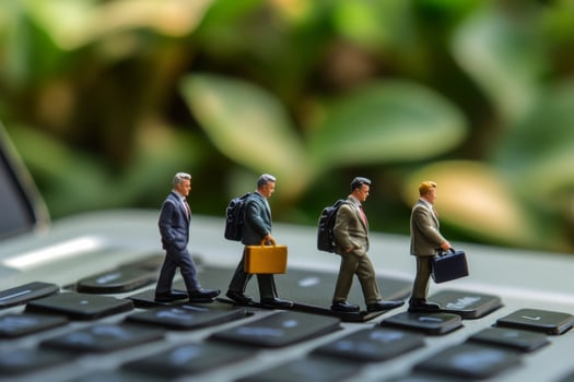 Businessmen figurines walking on laptop keyboard photo