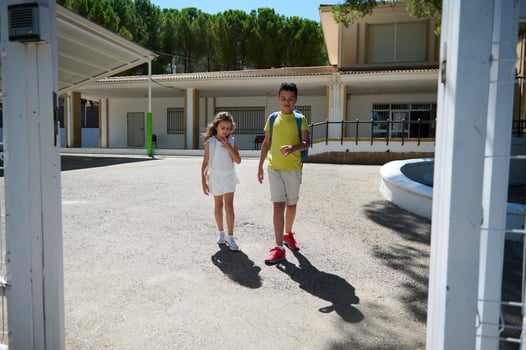 Two children walking outside school on a sunny day photo