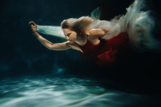 A girl in a red dress is swimming under the water.Journey under the water of a single woman.The concept of underwater tourism photo