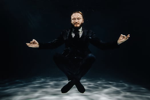 A man in a strict suit under water in the Lotus position photo