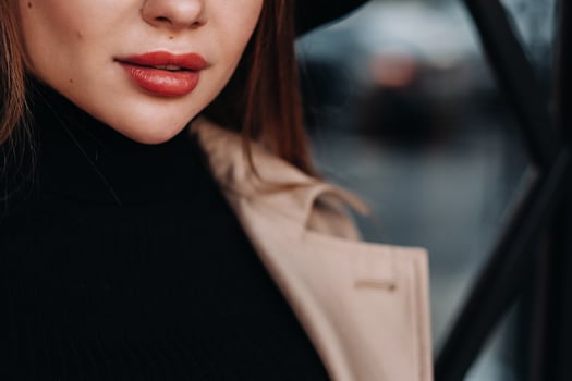 Close-up of the face and lips of a girl in a beige coat. photo