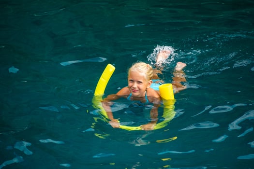 A happy girl swims on the Mediterranean Sea with the help of a yellow noodle. Marmaris, Turkey photo