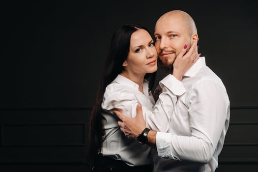 A man and a woman in white shirts on a black background.A couple in love in the studio interior photo