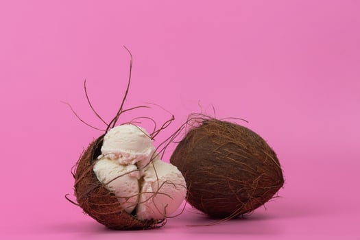 Vanilla ice cream balls in an empty coconut decorated with mint leaves on a pink background photo