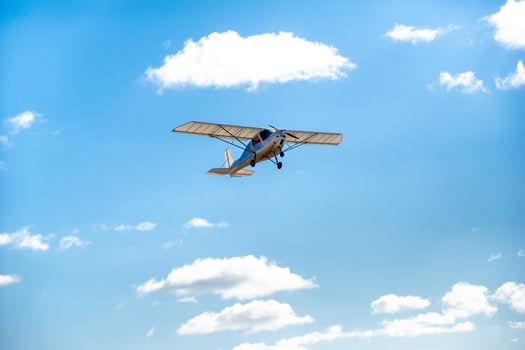 A small single-engine plane flying overhead against the blue sky photo