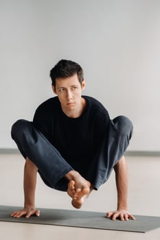 A man in a black T-shirt trains lying down doing stretches in the gym photo