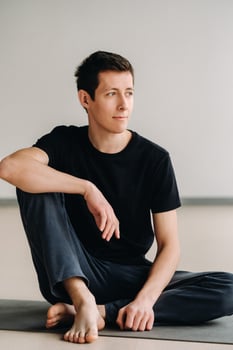 A male athlete in a black T-shirt is sitting in the gym before training and resting photo