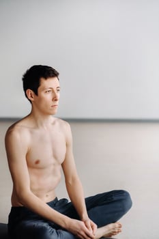 A male athlete with a bare torso is sitting in the gym before training and resting photo
