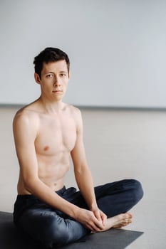 A male athlete with a bare torso is sitting in the gym before training and resting photo