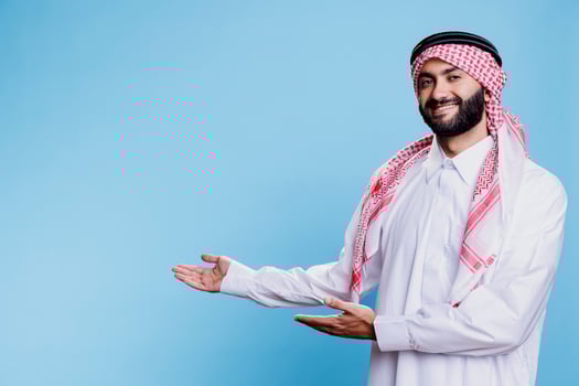 Arab man in thobe and ghutra pointing to side with hands, advertising product studio portrait. Muslim person wearing traditional clothes showing to right direction with arms photo