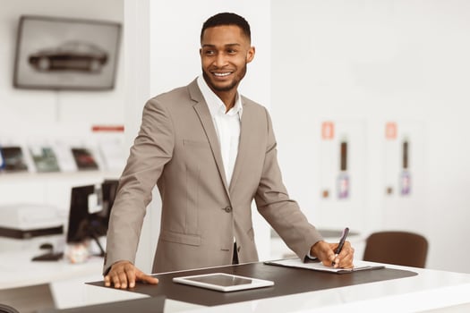 Selling Cars. Auto Dealer Man Standing At Counter Working In Automobile Dealership Office. photo