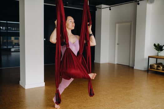 The girl is engaged in aerial yoga, doing stretching exercises on a hammock in the gym photo